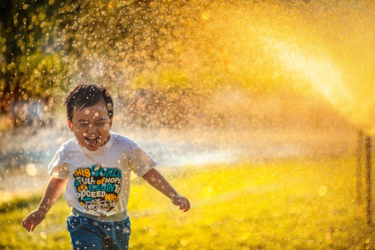child playing in sprinklers